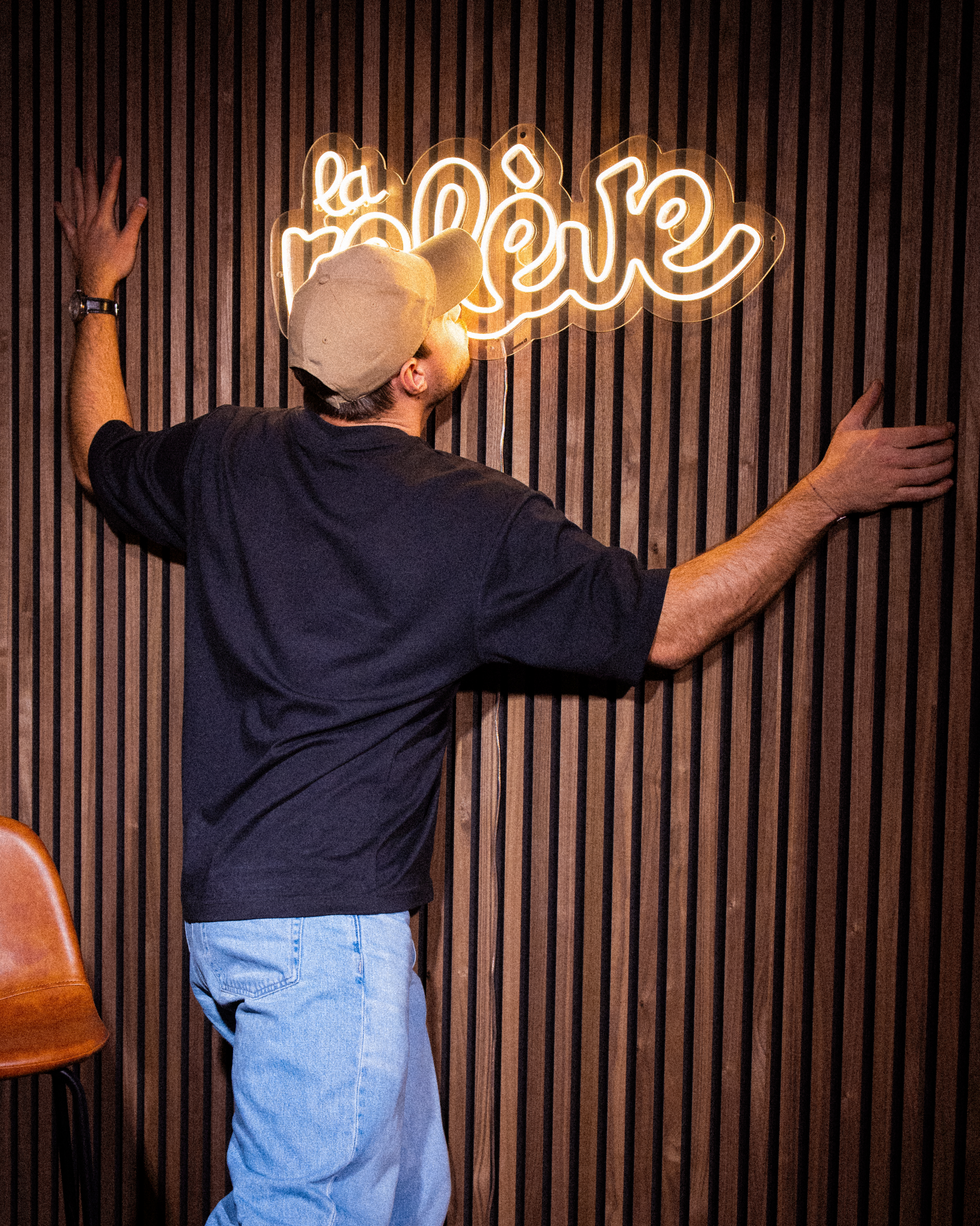 Un membre de l'équipe de La Relève devant l'enseigne néon du bar